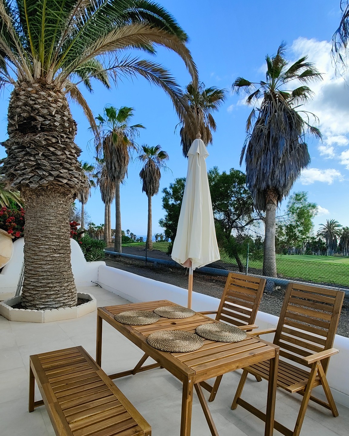Terrace seating area with palm trees and golf course view
